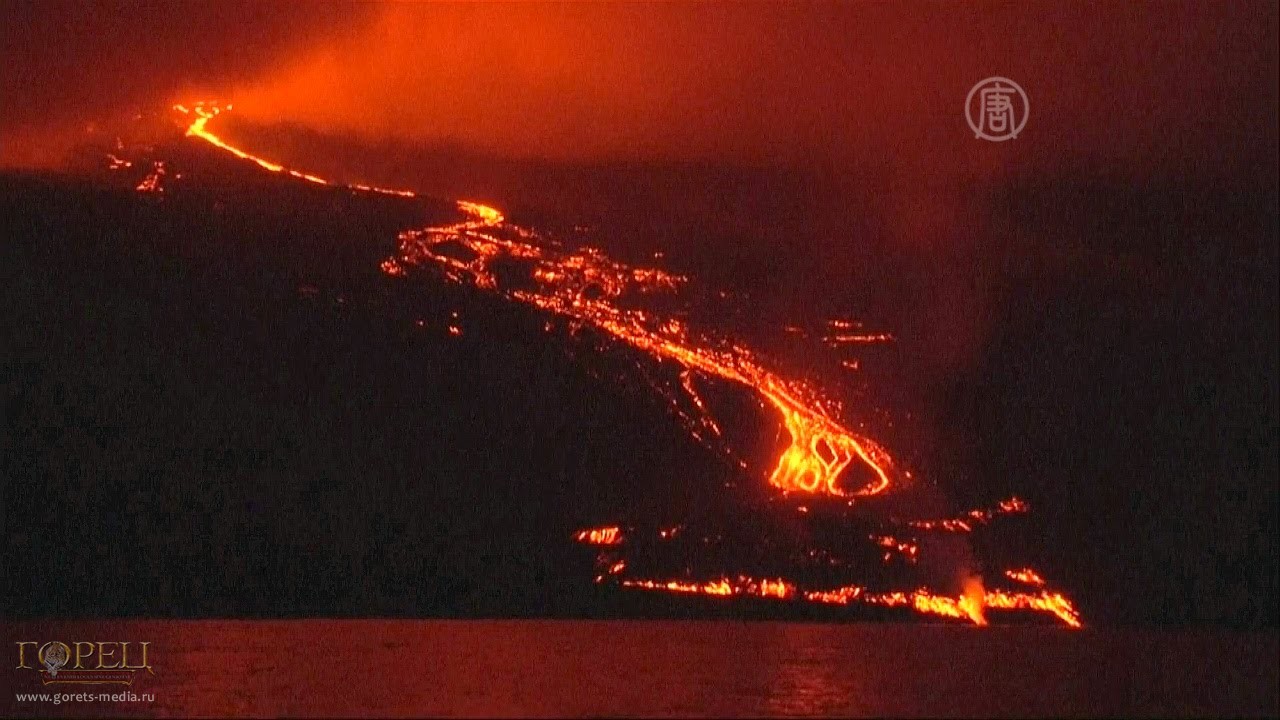 Огненная лава извергающегося вулкана Вольф стекает в океан